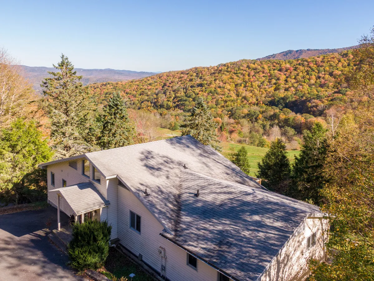 This image shows the house surrounded by lush green trees with a dramatic mountain range visible in the background. The scene evokes a sense of adventure and places the home in the heart of North Carolina’s mountainous landscape, perfect for outdoor activities and high country thrills.