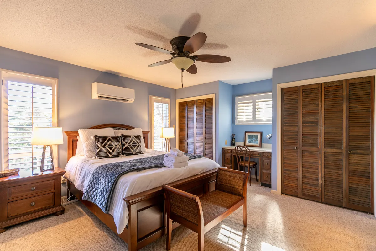 A bright, serene bedroom featuring a comfortable bed, matching nightstands, a spacious desk for working, and a large closet for storage. Natural light filters in, creating a relaxing atmosphere perfect for both rest and productivity.